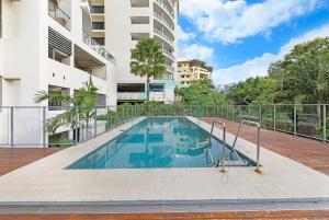 a swimming pool in front of a building at ZEN AT ARKABA 3BR Luxury Waterfront Apt Pool + BBQ in Darwin