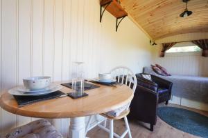 ein Esszimmer mit einem Tisch und einem Bett in der Unterkunft The Laburnum Retreat Shepherd Hut private hot Tub in Upper Hulme