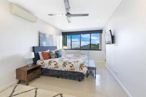 een slaapkamer met een bed en een raam bij ZEN AT ARKABA 3BR Luxury Waterfront Apt Pool + BBQ in Darwin