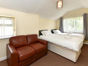 a bedroom with two beds and a leather couch at Pass the Keys Central Swansea townhouse 4B Mins from everything in Swansea