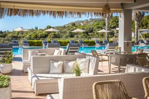 a patio with wicker chairs and tables and a pool at ASTRA Village Resort in Svoronata