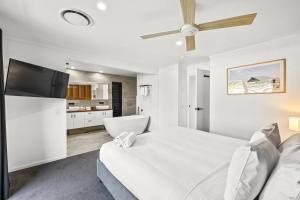 a white bedroom with a large bed and a flat screen tv at Ultra Modern & Relaxing Inner City 4bed House - with a Private Pool - 10mins walk to Beach in Gold Coast