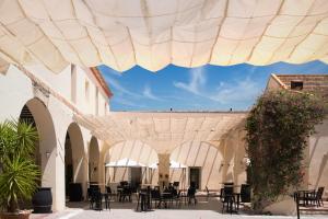 a patio with tables and chairs under a large umbrella at Hotel Palacio Marqu&eacute;s de Ariz&oacute;n in Sanl&uacute;car de Barrameda