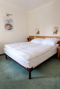 a large bed in a bedroom with white sheets at Hotel Zajazd Kultury, dawniej Pocztowy in Zielona Góra