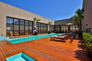 a building with a pool and a deck with tables at Comfort Suites São José do Rio Preto in Sao Jose do Rio Preto