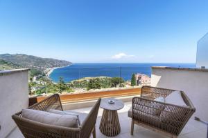 a balcony with chairs and a table and the ocean at Villa Fiorita Boutique Hotel in Taormina