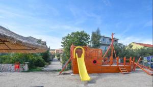 um parque infantil com um escorrega amarelo e um controle deslizante em Apartman Branka em Dobropoljana