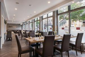 un comedor con mesas, sillas y ventanas en Novum Hotel City B Berlin Centrum, en Berlín