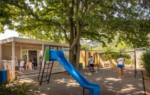 un parque infantil con un tobogán frente a una casa en Baška Beach Camping Resort by Valamar en Baška