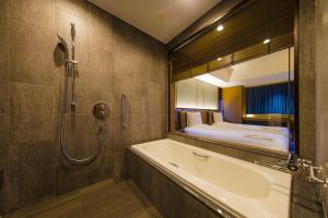 a bathroom with a tub and a bathtub at Hotel Collective in Naha