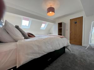 a bedroom with a large bed with white sheets and pillows at Pass the Keys By the Beach Brand New Holiday home in Littlestone-on-Sea