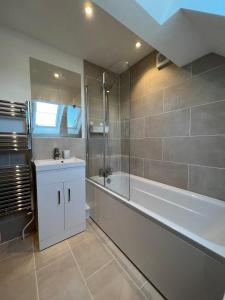 La salle de bains est pourvue d'une baignoire, d'une douche et d'un lavabo. dans l'établissement Pass the Keys By the Beach Brand New Holiday home, à Littlestone-on-Sea