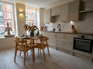eine Küche mit einem Tisch, Stühlen und einem Waschbecken in der Unterkunft Pass the Keys Luxury 2 bed apartment in Nottingham city centre in Nottingham