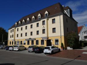 a large yellow building with cars parked in front of it at Hotel Zu den Drei Kronen in Donauwörth