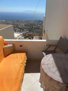 a couch on a balcony with a view of the ocean at Palaia katoikia Amazing View Pyrgos Santorini in Pyrgos