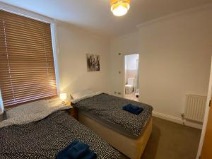 two beds in a room with a window at Cosy Beachfront Bournemouth 3-Bedroom 3-Bathroom Free Parking Free WiFi in Bournemouth