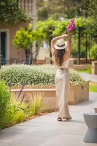 Thalassa Boutique Hotel - Adults Only في لاسي: امرأة في قبعة تحمل وردة وردية