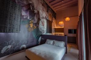 - une chambre avec un lit et une fresque murale fleurie dans l'établissement Casa del Cardenal, à Cordoue