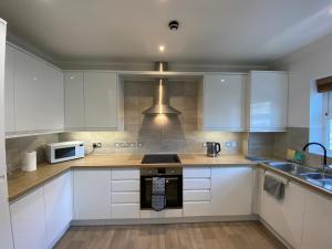 a kitchen with white cabinets and a microwave at Cosy Beachfront Bournemouth 3-Bedroom 3-Bathroom Free Parking Free WiFi in Bournemouth