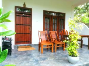 a porch with wooden chairs and a table and doors at The Cattleya Guest House in Sigiriya