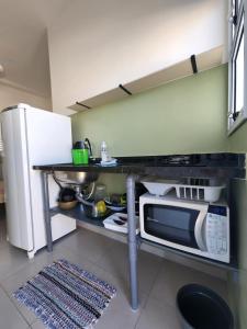 a kitchen with a counter with a microwave and a refrigerator at CHALES DO BONA MARANDUBA in Ubatuba