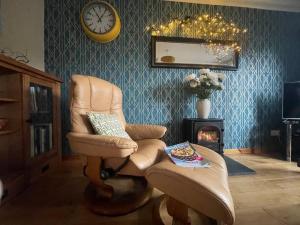 a living room with a chair and a fire place at Beautiful Peebles Bungalow in Peebles