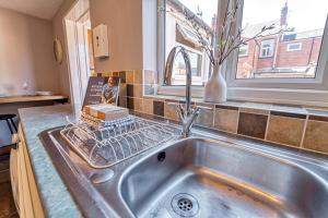 een wastafel in een keuken met een raam bij Guest Homes - London Road Cottage in Worcester