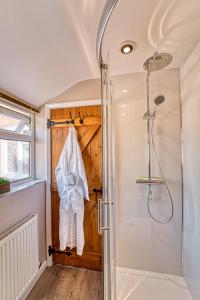 een badkamer met een douche en een houten deur bij Guest Homes - London Road Cottage in Worcester