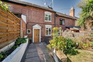 an exterior view of a brick house with a wooden fence at Guest Homes - London Road Cottage in Worcester