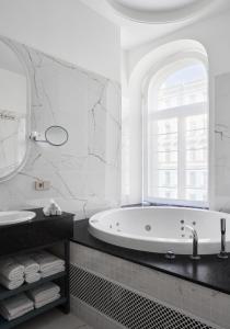 a white bathroom with a tub and a sink at Helvetia Hotel in Saint Petersburg