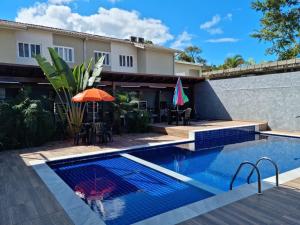 una piscina con sombrilla y una casa en CHALES DO BONA MARANDUBA, en Ubatuba