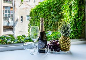 a bottle of champagne and a bowl of grapes and a pineapple at Aparthotel Cracovia Residence in Krakow