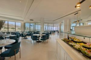 エイン・ボケックにあるHerbert Samuel Hod Dead Sea Hotelのテーブルと椅子、料理を提供するレストラン
