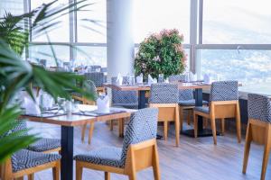 - une salle à manger avec des tables, des chaises et des fenêtres dans l'établissement Ubumwe Grande Hotel, à Kigali
