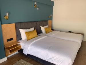 a bedroom with a large white bed with yellow pillows at Royal Hotel Rabat in Rabat