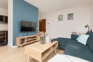 ein Wohnzimmer mit einem blauen Sofa und einem TV in der Unterkunft Chłodna Apartment European Square Warsaw by Renters in Warschau