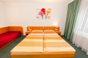 sypialnia z 2 łóżkami i czerwoną kanapą w obiekcie Pension La Mamma w mieście Aschach an der Donau