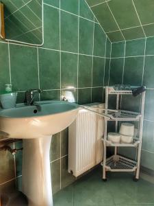 baño con lavabo y pared de azulejos verdes en Eszter Panzió, en Praid