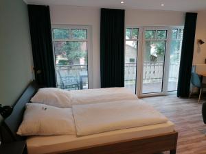 a bedroom with a bed and a balcony with windows at Gasthof Zumdohme in Lastrup