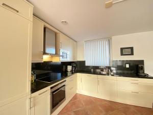 a kitchen with white cabinets and black counter tops at Callantsoger Staete A206 in Callantsoog +8 photos
