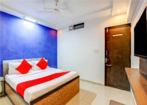 a bedroom with a bed with red pillows and a television at Hotel Sangam in Ahmedabad