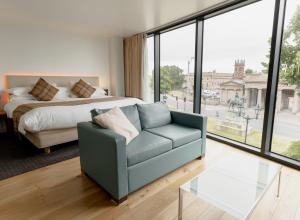um quarto com uma cama, um sofá e uma mesa de vidro em ABode Chester em Chester