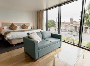 een slaapkamer met een bed, een bank en een glazen tafel bij ABode Chester in Chester