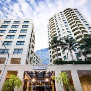 two tall buildings with palm trees in front of them at Parramatta Hotel Apartment in Sydney