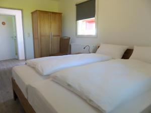 two beds in a bedroom with white sheets at Bernsteinreiter Erlebnishof Barth, Blockhütte 20 in Barth