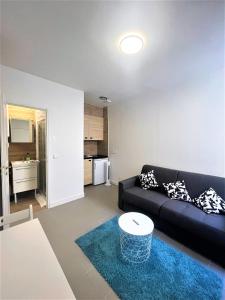 - un salon avec un canapé noir et un tapis bleu dans l'établissement Les Halles Appartements, à Paris