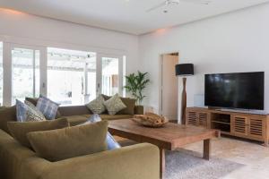 a living room with a couch and a table and a tv at Villa Jasper at BERAWA beach in Canggu