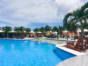 a pool at a resort with chairs and palm trees at The Ritz Village in Willemstad