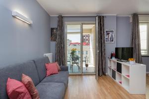 Sala de estar con sofá gris y TV en Le Chicche del Porto - Bleu en Génova