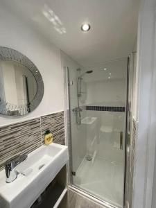 a bathroom with a shower and a sink and a mirror at Magnolia Passageway to the Jurassic Coast. in Stoborough